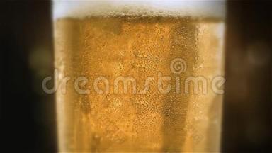特写慢镜头冷淡啤酒放在杯子里，酒吧背景上有水滴。 快来点啤酒。 <strong>微波</strong>炉