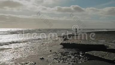 一个孤独的人在波涛汹涌的海洋的海岸上的剪影。 浪漫，孤独的概念