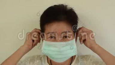亚洲老年妇女戴卫生口罩长袍保护口鼻免受病毒感染
