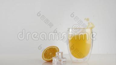 用冰块装饰在白色桌子上的玻璃杯中，冰块随着飞溅和气泡<strong>落入</strong>新鲜的橙汁或菠萝汁中