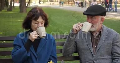 幸福的老家庭正在舒适的城市公园里的长凳上休息。 秋天，<strong>老人夫妻</strong>在公园里喝茶