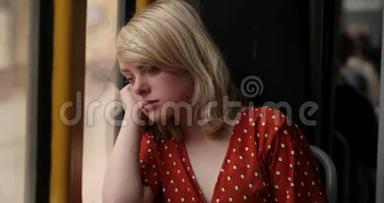 年轻疲惫的女人坐在电车上时看着窗外的肖像。 一位迷人的女士