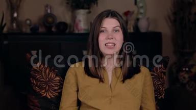 一个年轻的女孩，白种人的外表，坐在椅子上，嘴巴热身，排练一个演讲，然后录制一个vlog。