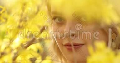 一位年轻迷人的女子，一头金色的<strong>秀发</strong>，在黄色花瓣的花树之间，亲密的肖像。 可爱可爱