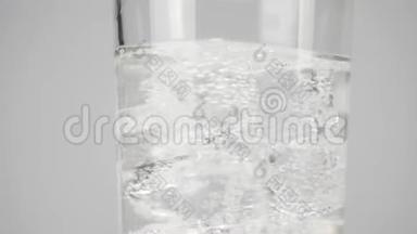 冰块旋转并漂浮在带有白色背景气泡的纯净淡水的玻璃中。 呆在家里吃饭的概念