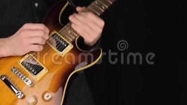 吉他手演奏一把浅棕色的六弦电吉他，在黑色背景下挑一把。 呆在家里的概念