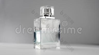 带有青色香水或精油的扁平表面瓶在灰色背景下慢慢旋转在白色桌子上