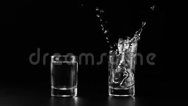 冰块随着溅起的水花和气泡掉落到两个玻璃杯中，杯中有伏特加、龙舌兰酒或黑桌上的清酒