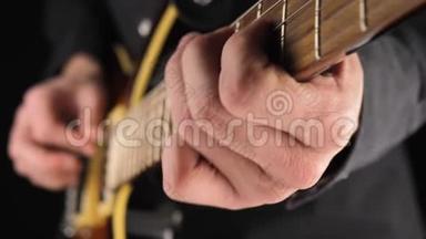 吉他手演奏一把浅棕色的六弦电吉他，在黑色背景下挑一把。 呆在家里的概念