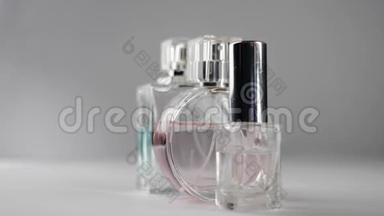 三瓶粉红色、青色和<strong>透明</strong>的香水或精油在白色桌子上慢慢地在<strong>灰色背景</strong>下旋转