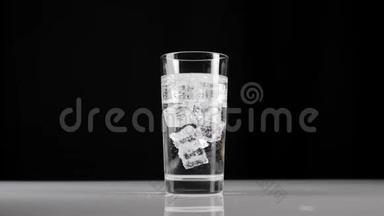 冰块在<strong>玻璃杯</strong>中旋转和漂浮，<strong>玻璃杯</strong>中有气泡或苏打水，背景为黑色。呆在家里的概念