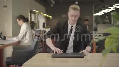 前景集中红发白种人男子坐在椅子上的桌子和打开笔记本电脑。 有自信的人