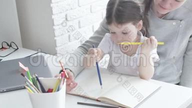 幸福的家庭，妈妈保姆教可爱的小女孩在桌子旁画画，妈妈帮小女儿<strong>学画画</strong>