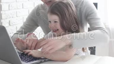 工作<strong>妈妈</strong>带着孩子在餐桌上。 忙碌的女人手里拿着婴儿在笔记本电脑上工作。 带着<strong>漂亮</strong>孩子的工作<strong>妈妈</strong>