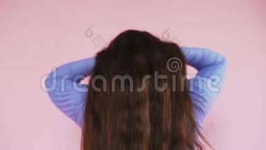 女孩在粉红色的背景上从后面露出她美丽的长姜发。 护发的课题.. 慢动作。