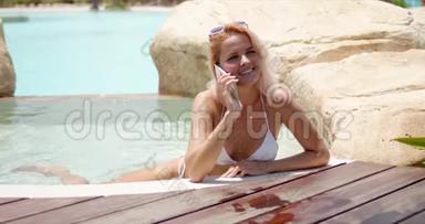 在游泳池游泳时，活泼的女人在智能手机上欢快地讲话