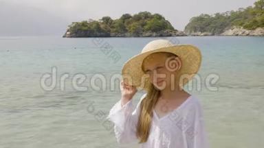 天堂<strong>海滩</strong>上戴草帽的可爱女孩肖像。 少女在<strong>夏日海滩</strong>阳光明媚的日子眯着眼睛。 年轻模特