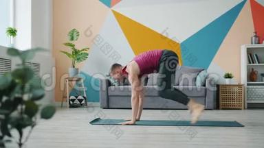 男瑜伽学生在家锻炼，在橡胶垫上做手臂平衡