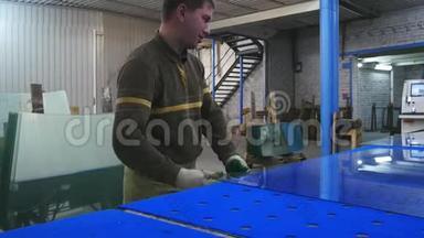 一个工人在一张蓝色的<strong>桌子</strong>上切<strong>玻璃</strong>，并把它放在柜台上。 浮<strong>玻璃</strong>。