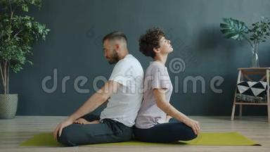 男女练习双人瑜伽，在工作室的垫子上做热身运动