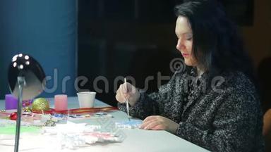 在一个冬天的晚上，一个年轻的女人用蓝色的水彩画雪花，为圣诞节做<strong>家居装饰</strong>