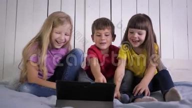 微笑的孩子们在<strong>家</strong>里放松的时候坐在床上看着<strong>数码</strong>平板电脑上的有趣视频