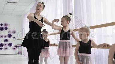 教师展示如何向小<strong>芭蕾</strong>舞演员跳舞.. <strong>芭蕾</strong>舞学校的女舞蹈演员学会跳舞。 年轻的<strong>芭蕾</strong>舞演员