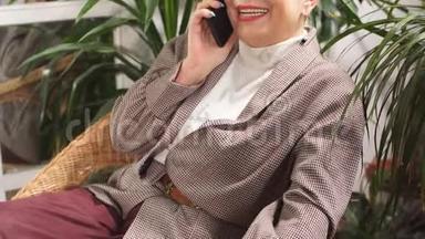 感情幸福的高级女士在商务中心用手机聊天