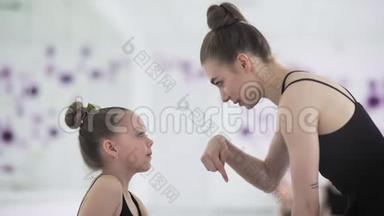 一位年轻的舞蹈老师和她的学生正在芭蕾舞工作室谈话