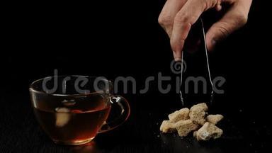 茶道。 手拿红糖，放在透明的杯子里，黑茶放在黑桌上，背景黑
