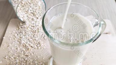 用带手柄的透明杯中的燕麦牛奶。 纯素替代奶牛乳制品。 不透明的奶油饮料倒入玻璃。 关闭-