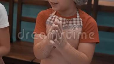 小男孩在烹饪课上擀面团之前用面粉搓手。 小男孩做饭准备面团