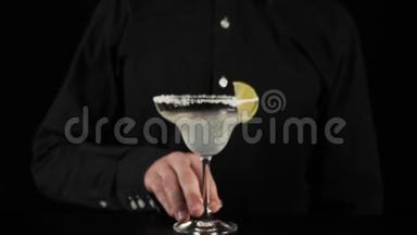 经典玛格丽塔鸡尾酒。 调酒师的手掌从一个杯子上取下玛格丽塔，杯边放一片石灰，以品尝鸡尾酒