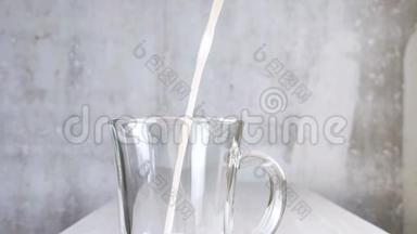 用带手柄的透明杯中的燕麦牛奶。 纯素替代奶牛乳制品。 不透明的奶油饮料倒入玻璃。 关闭-