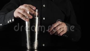 经典玛格丽塔鸡尾酒。 酒保拿着一个玻璃杯，放在一个黑色背景的波士顿摇床上