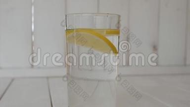 杯中冰的特写，杯中水和柠檬放在木制背景上。