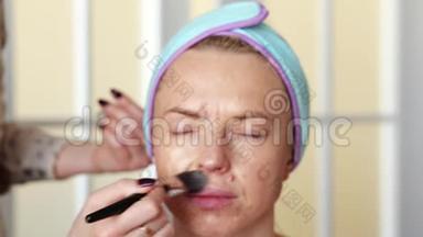 化妆师用画笔将<strong>粉底</strong>涂在女孩身上. 手术在家里进行。