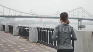 年轻的运动女子，身材瘦削，早上在雾中<strong>沿河</strong>奔跑。 参加运动的女运动员很难