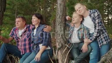 暑假快乐的一家人在针叶林拥抱。 母亲，儿子，父亲和女儿在松树上拥抱
