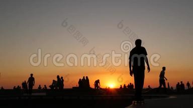 少年跳滑板的剪影骑长板，<strong>夏日夕阳</strong>背景.. 洛斯威尼斯海滨溜冰场
