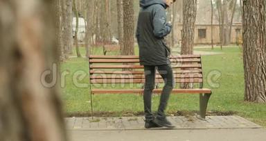 英俊的胡子男人坐在公园的长凳上拿着一本书，打开一本书翻页，开始阅读。 公园概念阅读