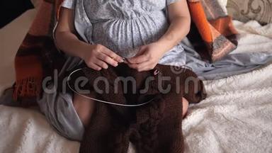 一位<strong>孕妇</strong>为她的孩子编织一件<strong>温暖</strong>的衣服，坐在床上，特写。