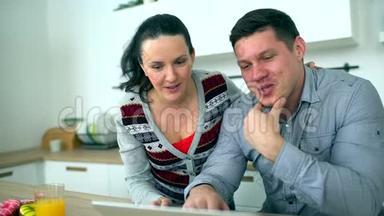 白人夫妇在厨房用电脑。 家庭、技术和<strong>人际关系</strong>概念-微笑的夫妻