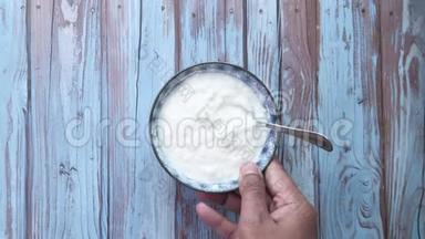 希腊酸奶在一个木制的碗在一个乡村木制的桌子上。