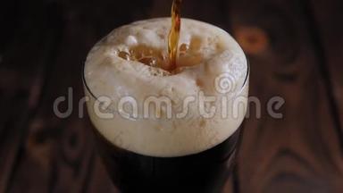 在木制背景下，一杯浓墨重彩的啤酒慢慢地倒在杯子里。