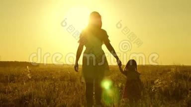 小女儿和妈妈牵着手在田野里走来走去。 宝贝牵着妈妈`手。 幸福的一家人傍晚走出家门