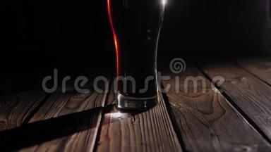 在黑色背景上的木制表面上特写一杯<strong>冰镇</strong>深色<strong>啤酒</strong>