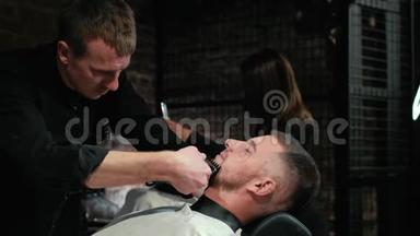 巴伯把客户的胡子剃在椅子上。 胡子的发型。 用电动剃须刀刮胡子。 装饰