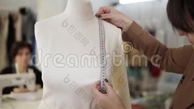 一位专业的女裁缝在制作一种新的时装时，用人体模型上的测量胶带进行测量