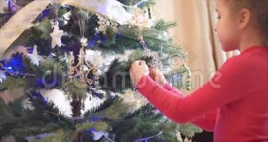 小女孩或小孩把新年`玩具挂在圣诞树上，装饰圣诞树。 圣诞节